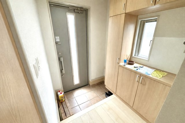 明るい木目調のシューズボックスが温かみを感じさせる玄関。収納力も高く靴や傘をすっきり整理できます。小窓付きで採光と換気も良好。家族の靴が多くても広々と使える、清潔感のあるエントランス空間です。　