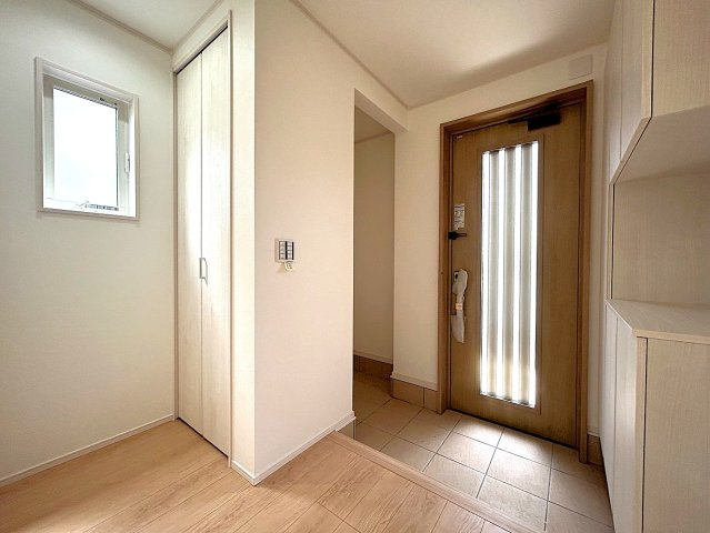 スリット入りの玄関ドアとホールの窓から自然光が入る明るい玄関。シューズボックスと土間収納・ホール収納で整理整頓された空間を保てます。