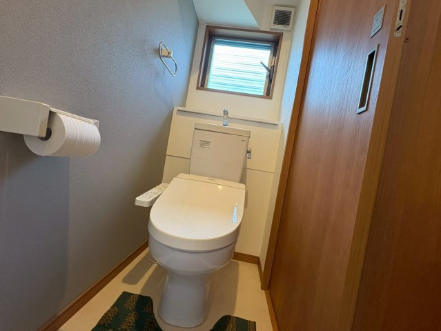 落ち着いた色合いのクロスが印象的なトイレは窓付きで自然光と換気がしっかり確保された快適な空間です。温水洗浄便座を備え毎日使う場所としての使い勝手も良好。スリムな空間ながら清潔感があり気持ちよく使えます