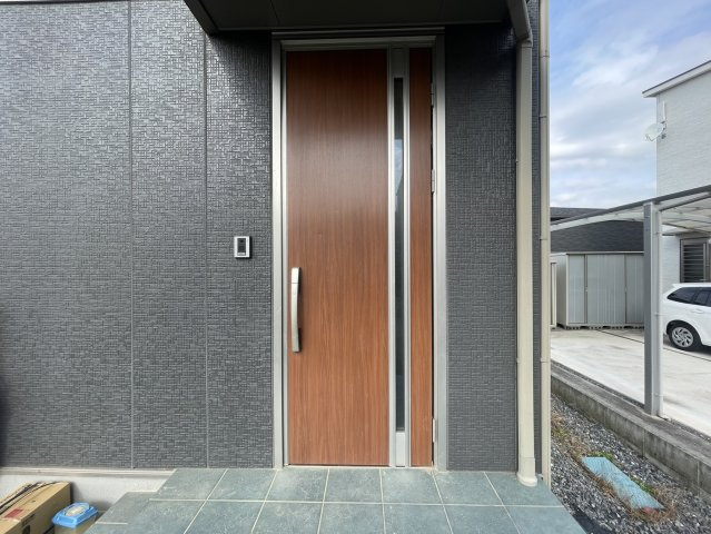 玄関ポーチは屋根付きで、雨の日でも濡れずに出入りできる安心のスペースです。落ち着いた色合いの外壁と木目調のドアが上品な雰囲気を演出。来客時の印象も良く、日常の使いやすさも兼ね備えた玄関まわりです。