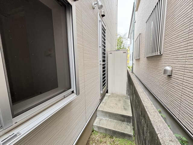 建物側面には勝手口へ続くスペースが確保されており、洗面室から直接出入りできる便利な動線となっています。外部収納や設備機器の配置スペースとしても活用しやすく、建物まわりを効率的に利用できます。