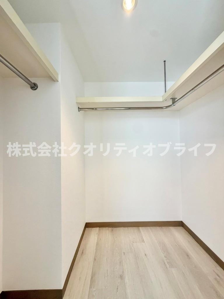 ハンガーパイプと上部棚を備えた、奥行きのあるウォークインクローゼット。ロングコートから季節物の大きな荷物まで整然と収納でき、居室を広々と美しく保つ大容量の空間です