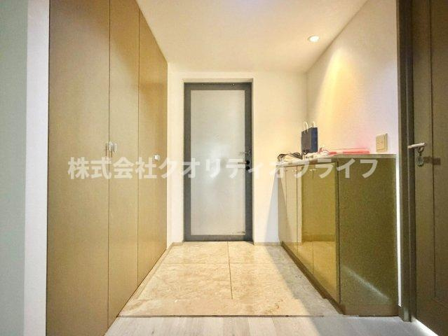 両壁面に配された大型シューズ収納により、靴からお出かけ用品まで整然と収まります。インテリアを飾れるカウンターと温もりあるライティングが、日々の帰宅を優雅に心地よく彩る洗練された意匠です