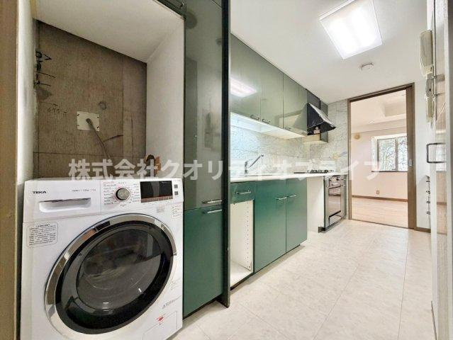 シックな深緑のキャビネットが重厚感を演出。本格的なお料理を楽しめるビルトインオーブンに加え、洗濯機を設置できるユーティリティスペースも配した、機能性と意匠美を極めた上質な調理空間です。