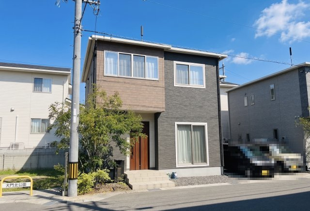 落ち着いたダークカラーと木目調の外壁が調和した、洗練された外観デザイン。前面道路に面しており視認性も良く、開放感のある立地です。駐車スペースも2台確保されており、ご家族でのお車利用にも安心です。