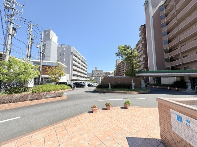 前面道路側から見たマンション外観です。歩道と車道が整備され、敷地周辺には植栽も配置されています。建物と道路との位置関係や周辺の街並みなど、現地での暮らしをイメージする際に確認しておきたいポイントです。
