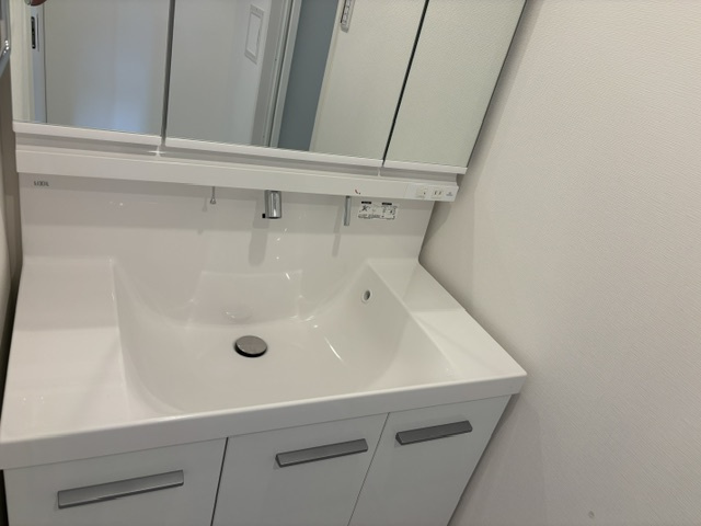 お手入れ簡単なハイバックガードデザインの洗面ボウル。水栓の根元に水がたまらない壁付け水栓を採用し、気になる水垢汚れをシャットアウトします。2025年12月新規交換済みの清潔な水回りです。