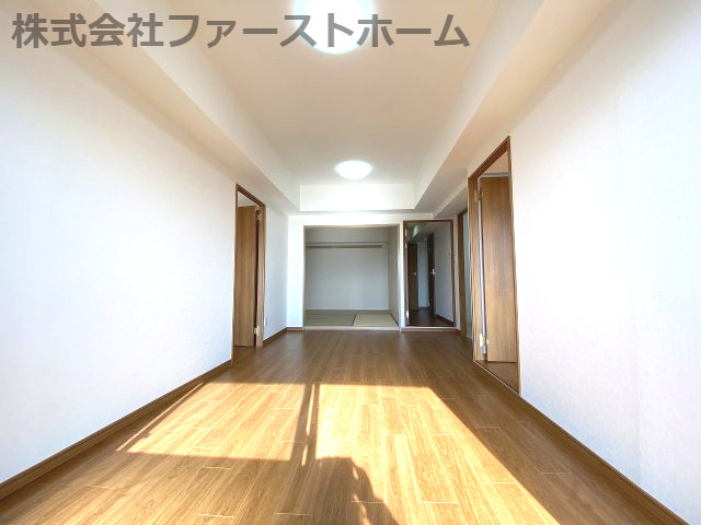 白い壁と温かみのあるフローリングが清潔感を演出するリビング。直線的な空間が奥行きを感じさせ、様々な家具配置を楽しめます。
