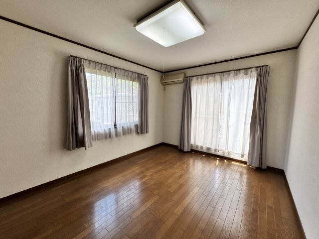 温かみのあるフローリングが魅力的な、明るく開放感のある洋室。2面に窓が配置されているため風通しが良く、1日を通して心地よい自然光が室内に差し込みます。シンプルで飽きのこない内装が、家具を引き立てます。