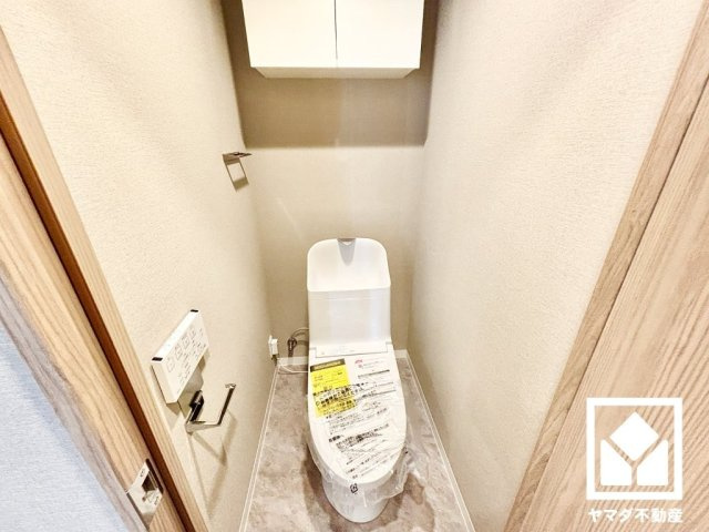 明るく清潔感溢れるトイレです。温水洗浄便座付きで、季節を問わずいつでも温かい便座をお使いいただけます。トイレットペーパーのストックや消耗品置き場などとしてお使いいただける吊戸棚も備えています。