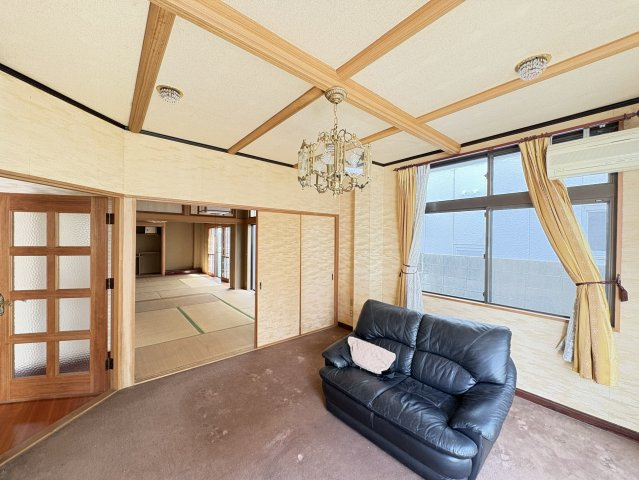 落ち着いた雰囲気のリビング空間で、ゆったりとくつろげる広さが魅力です。隣接する和室とつなげて使用することで、さらに広々とした空間として活用可能。天井デザインも特徴的で、上質な居住空間を演出しています。