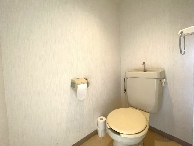 便器上部には手洗い器が備わっており、使用後にその場で手を洗える実用的な仕様。タオル掛けやペーパーホルダーなど、日常使用に必要な設備も設けられています。白を基調とした内装で圧迫感を感じにくい。