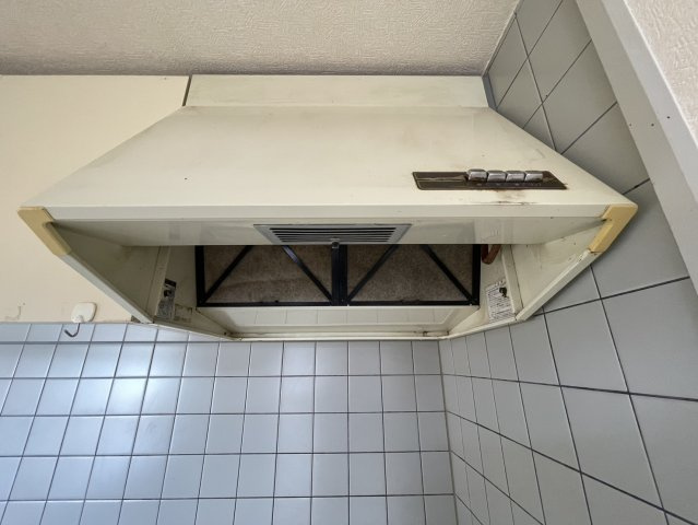 キッチン上部にはレンジフードを設置。調理時に発生する煙やにおいを換気するための設備で、毎日の料理に欠かせない設備のひとつ。壁面にはタイルが施工されており、キッチンらしい実用性を備えたつくり。