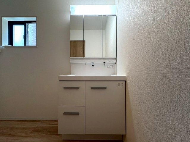 4号棟　鏡の裏には豊富な収納量を確保した、三面鏡タイプの洗面化粧台。化粧品やティッシュボックス、歯ブラシなどを機能的に収納できるスペースを設けました。いつもキレイに保ちたい洗面室の整頓にも役立ちます。