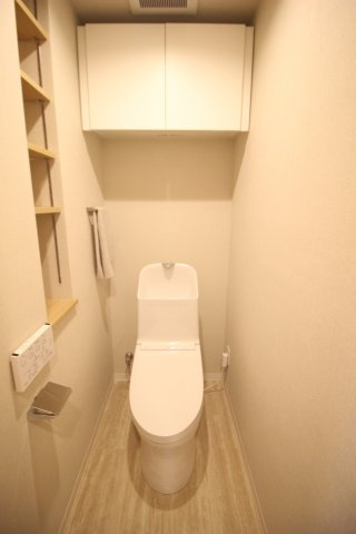 温水洗浄便座付きのトイレ。上部の吊戸棚だけでなく、壁にも棚が設けられています