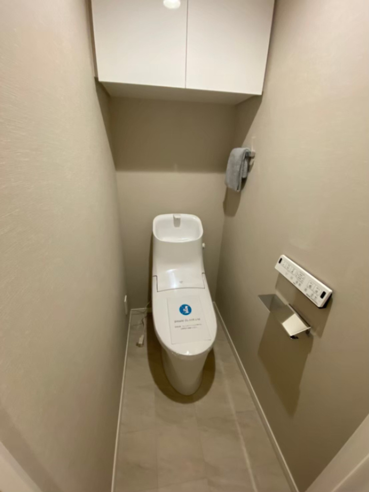温水洗浄機能付きです。上に戸棚があるので、トイレットペーパー等収納可能です。