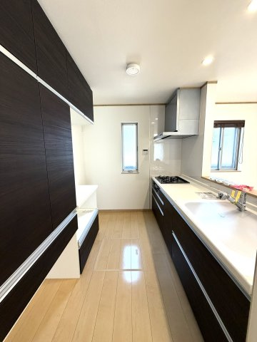 使い勝手の良いシステムキッチン。作業動線に配慮した設計で、調理から片付けまでスムーズに行えます。背面には食器棚を備え、大容量収納が叶います。