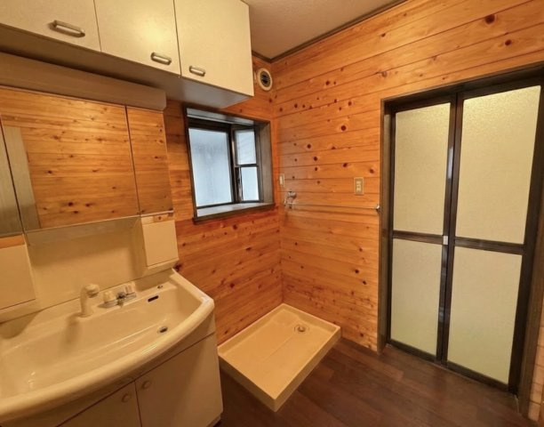壁一面に広がる木目がやさしい印象を与える洗面室。三面鏡付き洗面台は身だしなみチェックに便利。シャワー付き水栓のため、洗髪やお掃除もスムーズ。窓付きで自然換気ができ、湿気がこもりにくい快適な空間です。