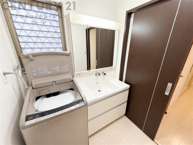 窓付きで明るく換気もしやすい洗面室。収納力のある三面鏡付き洗面化粧台を備え、朝の身支度もスムーズ。洗濯機置場も確保された、清潔感のある使いやすい空間です。（AＩで画像修正済み）