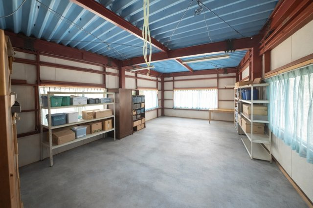 広々とした物置スペースは、棚を活用して効率よく収納可能。窓も複数あり明るさと換気を確保しています。事業用在庫や趣味の道具、大型荷物の保管にも対応できるゆとりある空間です。　