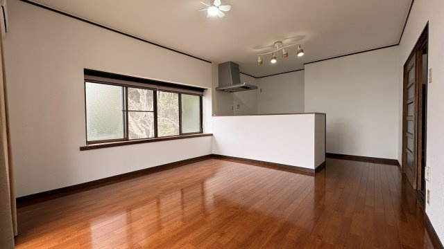 大きな窓から自然光が差し込む明るいLDK。フローリングの色味が落ち着いた雰囲気を演出し、家具の配置もしやすい整形空間です。対面式キッチンを採用しており、家族と会話をしながら料理が楽しめるのも魅力です。