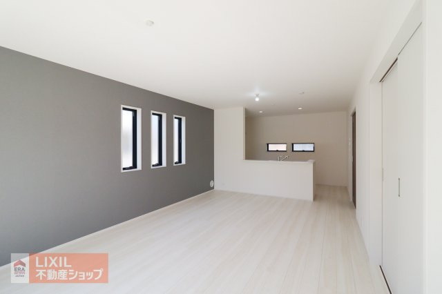 【リビングダイニング】現地完成写真。白を基調とした明るいフローリングが採光を優しく照らしより明るい印象に。アクセントクロスがおしゃれなリビング。明るい日差しの入るリビングは家族団らんの場所♪