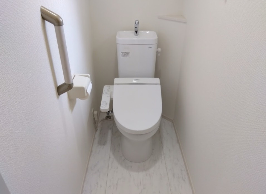 手すり付きで足腰に優しい、清潔感あるトイレです。温水洗浄便座や手洗い付きタンクで使い勝手の良さも魅力です。