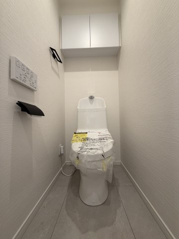 モノトーンのホルダー類とグレーの床面が引き締まった印象を与えるお洒落なトイレ。
