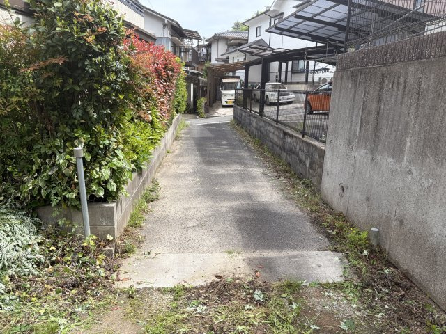 植栽の緑が並ぶ専用通路。道路から奥まっているためプライバシーを保ちやすい立地。