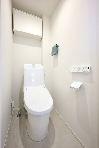 上部に扉付きの吊戸棚を備えた、すっきりと片付くトイレ空間。トイレットペーパーや掃除用具を目隠しして整理でき、温水洗浄便座を完備した衛生的で快適な設備仕様となっています。
