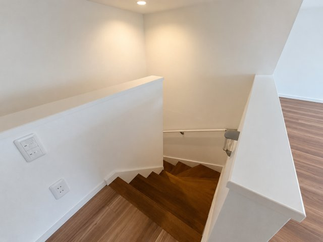 小屋裏収納へつながる階段ホールは手すり付きで安全性にも配慮された設計。シンプルで落ち着いた内装が住まい全体に統一感を与えます。階段部分にも自然光が入り開放感のある空間に仕上がっています。