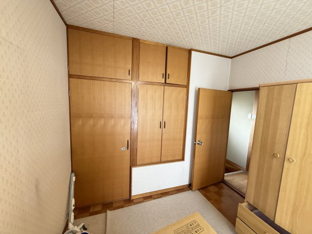 壁一面に設けられた収納は上下に分かれた大容量タイプで布団や衣類、小物まで効率よく整理できます。木目調の扉が室内に温かみを添えすっきりとした印象に。洋室の雰囲気を損なわず実用性を兼ね備えた便利な空間です