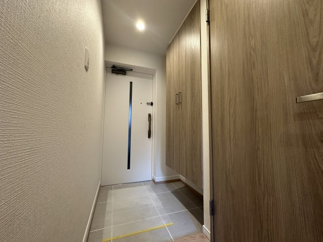 白い玄関ドアと、木目のシューズボックスの扉が、おしゃれなすっきりとしたデザインの玄関です。