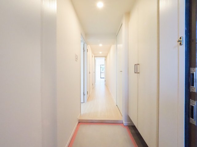 玄関から室内を見渡したアングルです。奥行きを感じさせる奥行きある廊下が伸び、その先には明るいリビングが広がります。扉を開けた瞬間に開放感と温かみが伝わる、家族や来客を心地よく迎えるレイアウトです。