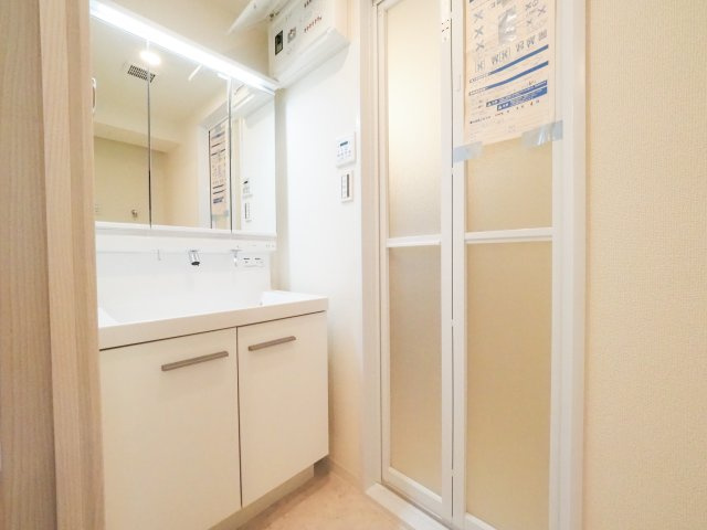 清潔感ある明るい洗面化粧台です。三面鏡の裏側や足元には充実した収納スペースを備えており、洗面用具や日用品をすっきり整理整頓できます。新規リフォームにより、毎朝の身支度を気持ちよく行える清潔な空間です。