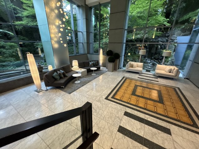 光と緑に満たされた、2層吹き抜けの贅沢なロビー空間。高級ホテルを思わせる上質な家具が並びます。