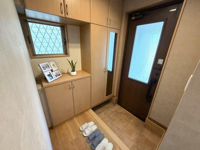 シックな玄関ドアと温かみのある木目調収納が調和した上質な玄関。飾り棚スペースには写真立てや観葉植物、鍵などを置いて、自分好みのウェルカムスペースを作れます。
