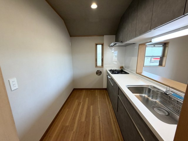 落ち着いたカラーの天井クロスが空間をおしゃれに演出。奥には自然光を取り入れる縦すべり出し窓があり、匂いがこもりがちなキッチン周りの換気にも便利です。
