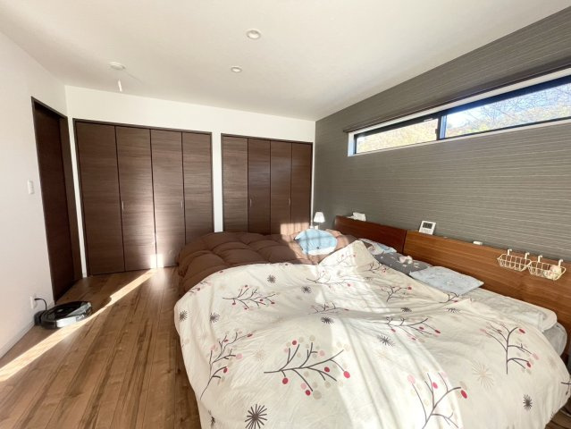 落ち着いた濃色クロスと横長窓が印象的な主寝室。朝日がやわらかく差し込み、穏やかな目覚めを迎えられる空間。壁一面に備わるワイドクローゼットで収納力◎。ベッドを並べてもゆとりがあり家族で快適に過ごせます。