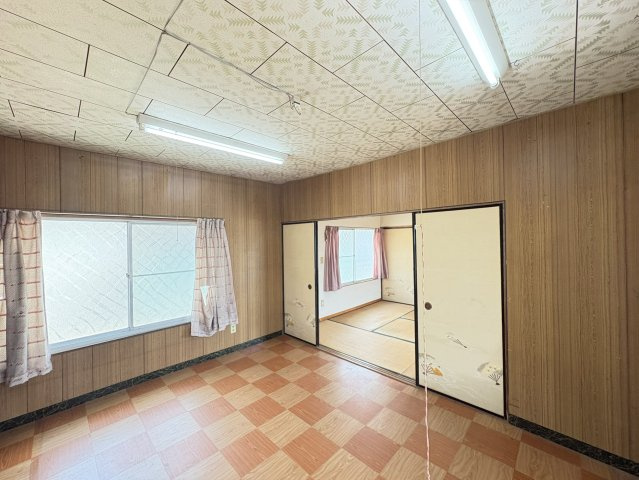 木目調の内装が落ち着いた雰囲気を演出する洋室です。大きな窓から自然光が入り、明るく開放感のある空間で快適に過ごせます。隣室との行き来もしやすく、寝室や子ども部屋、書斎など幅広い用途に対応可能。