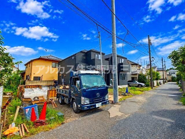 青空の下、順調に施工が進む新築分譲地。前面道路に面した開けた立地で、陽当りや周辺環境の良さが伺える現地写真です。