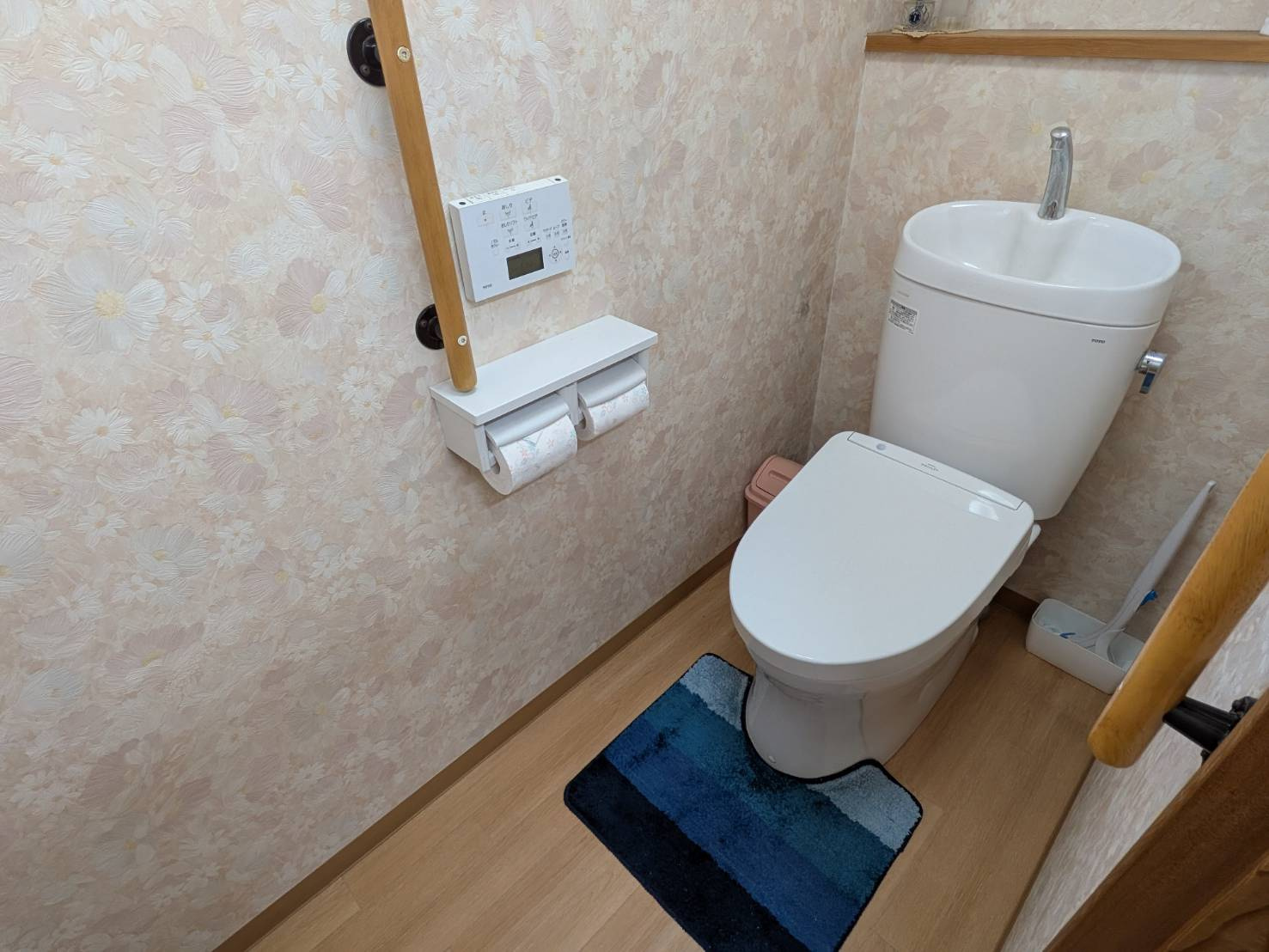 落ち着いた色合いの内装でまとめられたトイレ空間。手すり付きで安心して利用でき、操作パネルも備わっており快適性にも配慮されています。清潔感があり、日常使いに十分な設備が整った使いやすい空間となっています