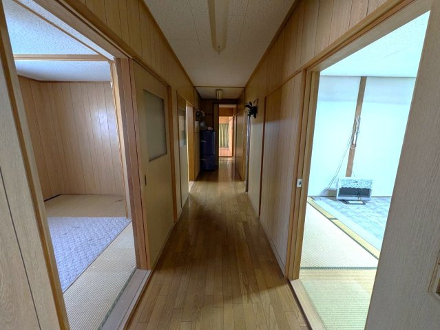 各居室へとつながる廊下は、動線が分かりやすく移動しやすい設計。木の温もりを感じる内装で、落ち着いた雰囲気が広がります。複数の部屋へアクセスしやすく、大家族での生活にも配慮された間取りです。