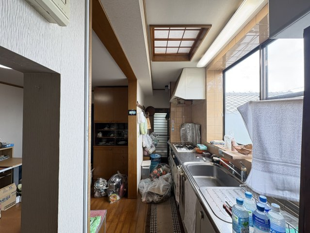 窓から光が差し込むキッチンは、作業スペースとシンクが広く、日々の料理を快適にサポートします。横長のレイアウトは動線がスムーズで効率的に使える設計。木目調の床や収納とも調和しており、家事導線の良さが魅力