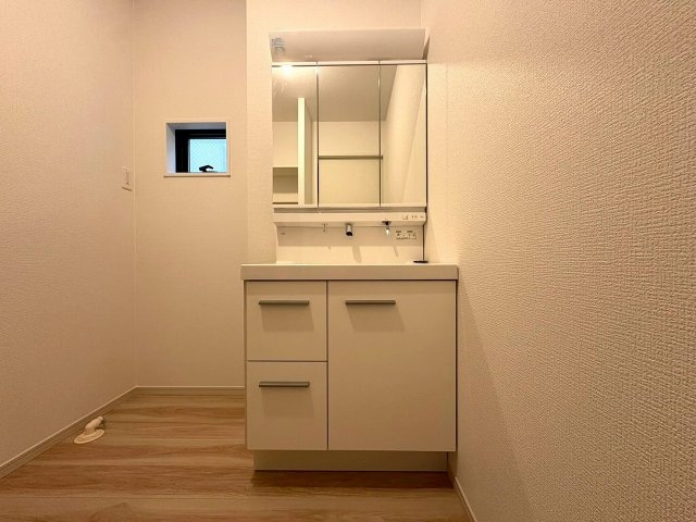 1号棟　鏡の裏には豊富な収納量を確保した、三面鏡タイプの洗面化粧台。化粧品やティッシュボックス、歯ブラシなどを機能的に収納できるスペースを設けました。いつもキレイに保ちたい洗面室の整頓にも役立ちます。