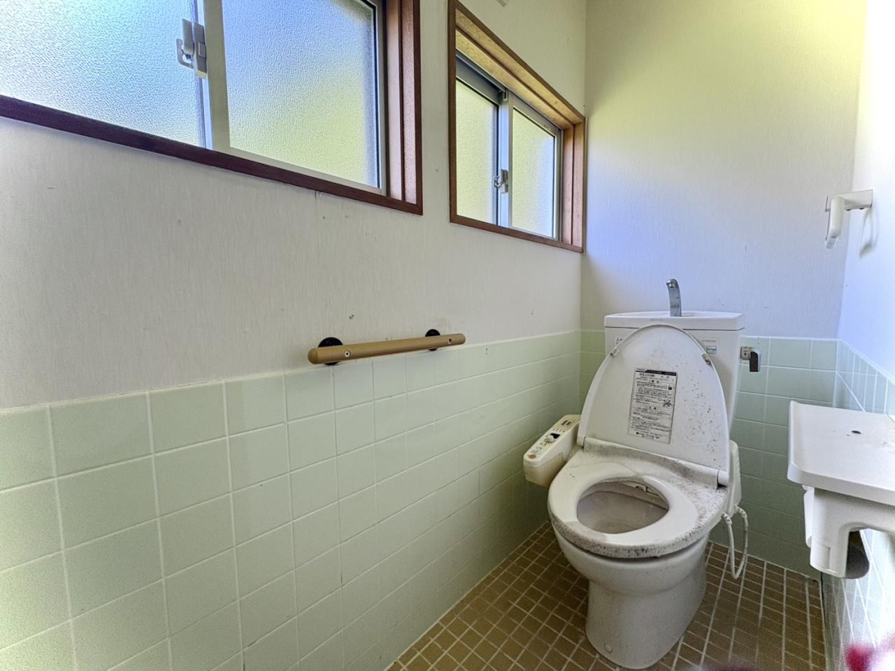 窓が2カ所にあり、自然光が差し込む明るいトイレです。温水洗浄便座付きで快適にご利用いただけます。壁面には手すりが設置されており、立ち座りの動作もスムーズです。