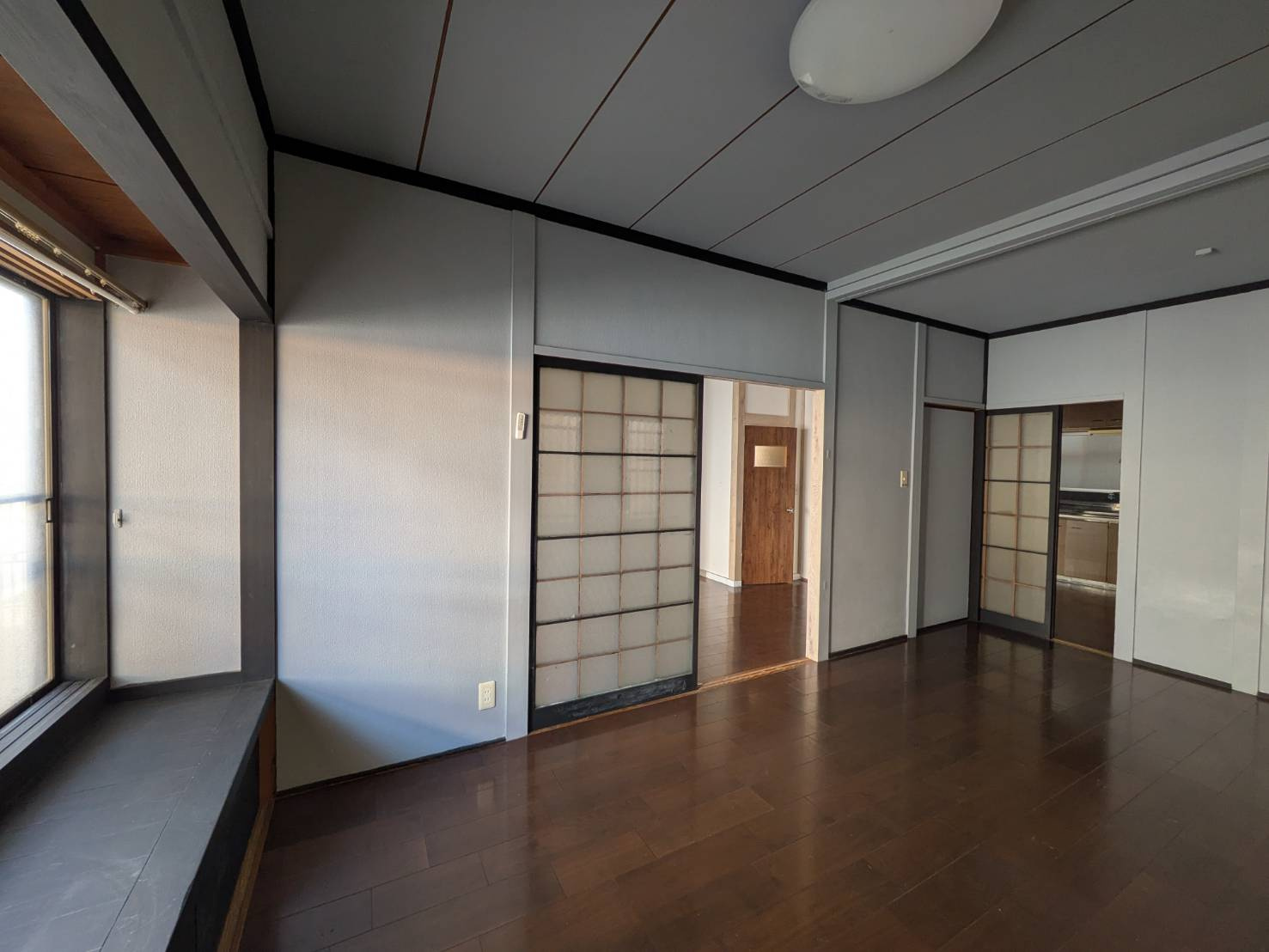 落ち着いた色味のフローリングが広がるリビング空間。大きな開口部から自然光が差し込み、明るさを確保しています。隣室とのつながりもあり、間取りの使い方次第で広々とした空間演出が可能です。