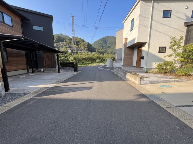 前面道路の様子です。道路から敷地への出入りがしやすく、駐車スペースへもスムーズに進入できる配置となっています。周辺は戸建住宅が並ぶ落ち着いた住環境で、身近に緑豊かな景色を感じられるのも魅力です。