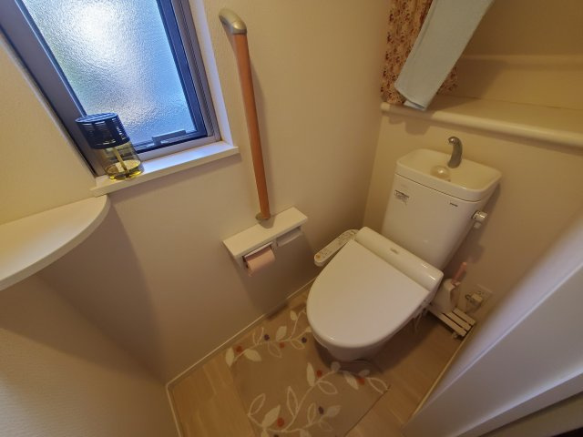 採光と換気ができる窓付きのトイレです。立ち座りをサポートする手すりや、トイレットペーパーのストックに便利な棚も完備。温水洗浄便座付きで快適にご利用いただけます。