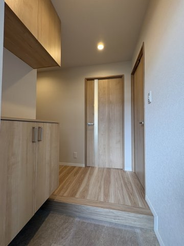 木目の美しいフローリングと建具が心地よい空間を演出する玄関。セパレート型のシューズボックスを採用し、カウンター部分には小物を飾ることも可能です。ダウンライトが優しく空間を照らします。